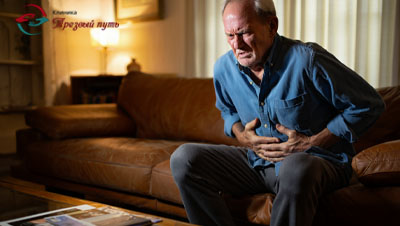Мужчина пожилой сидит на диване и держится за живот